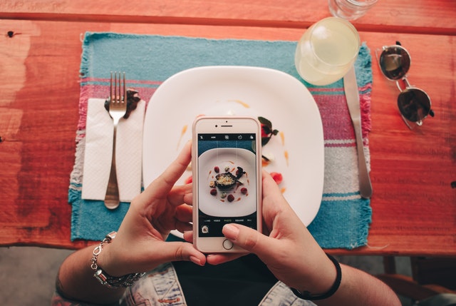 Človek si na mobil fotí jedlo na tanieri